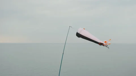 A windsock flutters in a strong wind, showing the direction and speed of the Stock-Footage 172254555