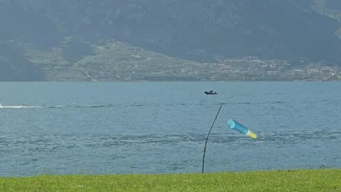 Windsock in paraglider landing zone shows lake shore breeze direction 스톡 동영상 313710481