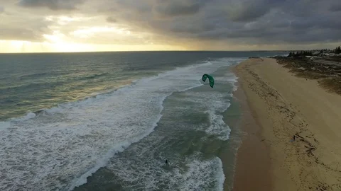 Windsurfer on a beach at sunset pull back and reveal aerial footage Stock Footage 107532380