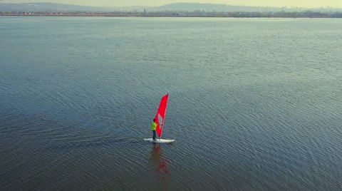 Windsurfer on lake with red sail fly over aerial shot slow motion Stock Footage 47533425