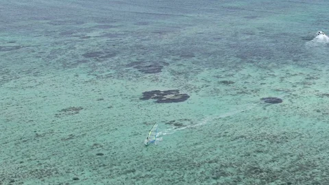 Windsurfer making fordewind turn on shallow lagoon water aerial shot Stock Footage 120426144