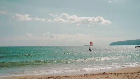 Windsurfer managing a sail of a windsurf board while floating near sea coast Video stock 219398384