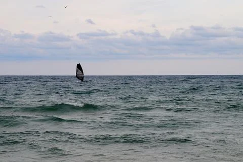 Windsurfer on open sea under cloudy sky Stock Photos