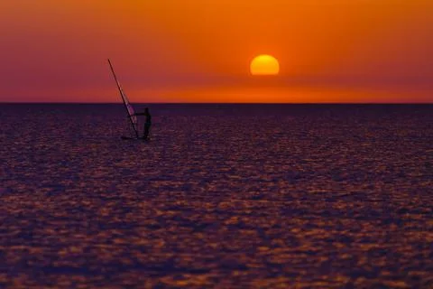 Windsurfer silhouette against sun 스톡 사진
