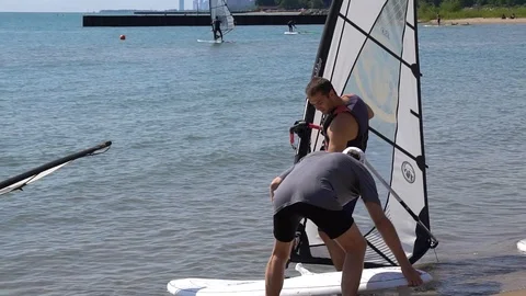 WINDSURFER WALKING HIS FLOATING BOARD OUT INTO THE WATER Stock Footage 106091937