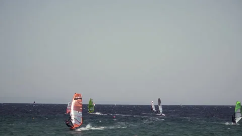 Windsurfing lessons in a bit wavy sea - long shot of windsurfers in the sea  Stock Footage 159563042