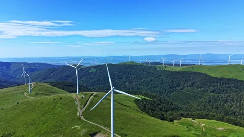 Windswept hills show many wind turbines turning in the breeze above green fields Stock Footage 337919203