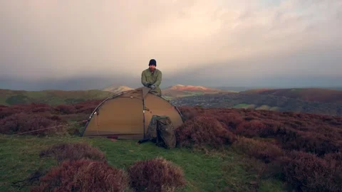 Windy conditions as an explorer sets up a tent on an English hill Vídeos de archivo 296242423
