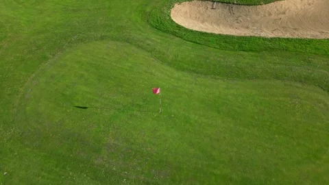 Windy day on the golf course, visible in the angled lean of the small red flag Stock Footage 322088486