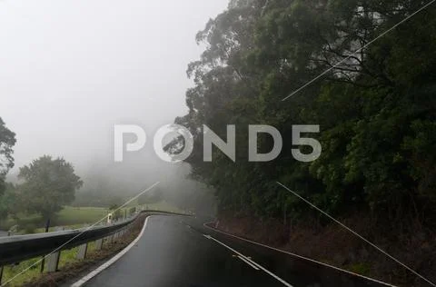 Windy mountain road at fog. Dangerous driving conditions metaphor Stock Photos