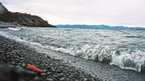 Windy waves rolling onto rocky shoreline under overcast sky Stock Footage 320897210