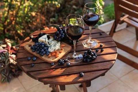 Wine and cheese platter on rustic garden table at sunset Stock Photos