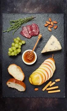 Wine appetizers set: cheese brie and grapes, honey,nuts, pears on board on .. Stock Photos