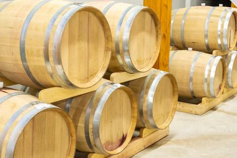 Wine barrels stacked in rows inside a winery cellar aging Stock Photos