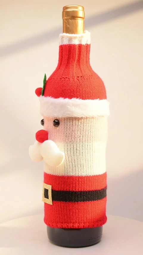 A wine bottle dressed in a festive Santa Claus-themed knitted cover on white Stock Footage 320536344
