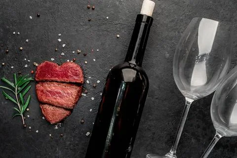 Wine bottle with two empty glasses and steak on black table Stock Photos