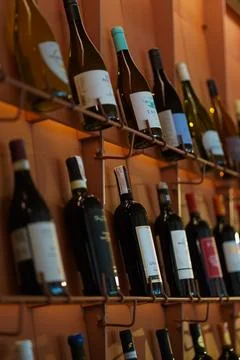 Wine bottles of different varieties displayed on wooden shelves in a wine sho Stock Photos