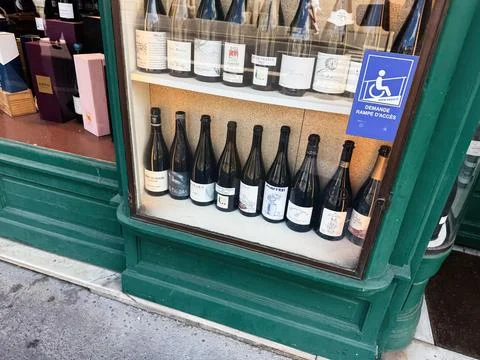 Wine bottles displayed in a green storefront window at a Paris, France bout.. Stock Photos