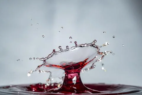 Wine drop falling and colliding with another one, creating an explosive crown Stock Photos