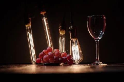 Wine glass empty and grapes next to it on a dark wooden table against the bac Stock Photos