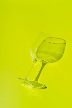 Wine glass lies on lemon green background. Stock Photos