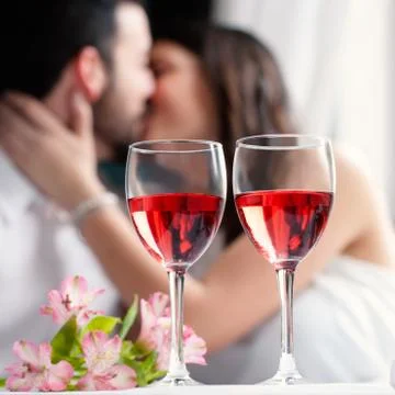 Wine glasses with couple kissing in background. Stock Photos