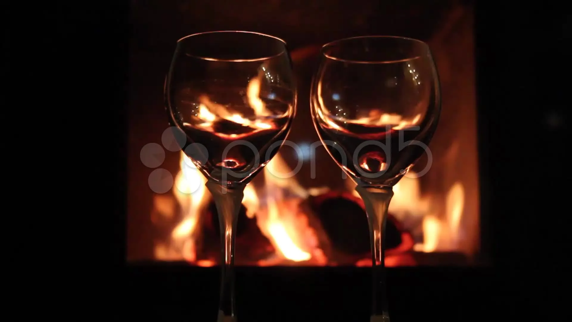 Mulled wine glasses on table in front of burning fireplace. Stock