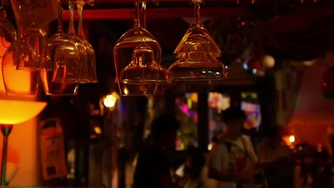 Wine glasses hanging upside down from bar ceiling rack 動画素材 333834167
