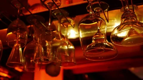 Wine glasses hanging upside down from bar ceiling rack Видео 333834177