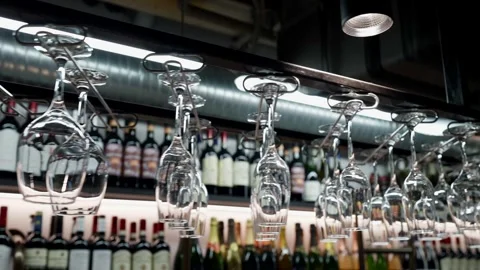 Wine glasses hung upside down in a stylish bar, with bottles of wine and champag Video stock 291645237