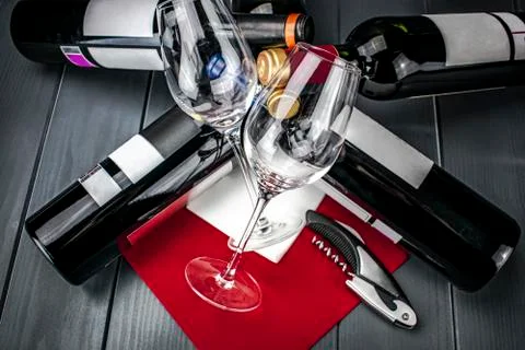 Wine glasses lying on bottles of red wine , corkscrew, napkin and gray wooden Stock Photos