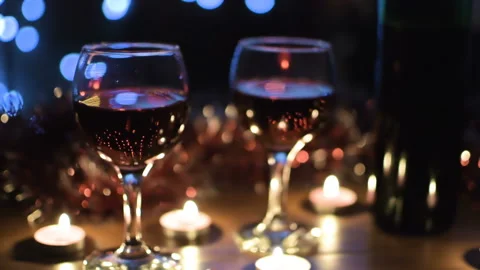 Wine glasses with red wine closeup. Light garlands in the background. Video stock 97366702
