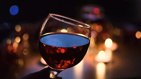 Wine glasses with red wine closeup. Light garlands in the background. Video stock 97367435