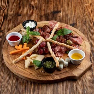 Wine platter with assorted snacks such as grissini, cheese, sliced meat and n Stock Photos