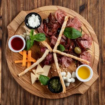 Wine platter with assorted snacks such as grissini, cheese, sliced meat and n Stock Photos