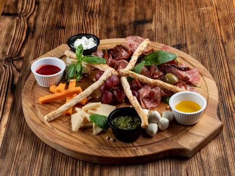 Wine platter with assorted snacks such as grissini, cheese, sliced meat and n Stock Photos