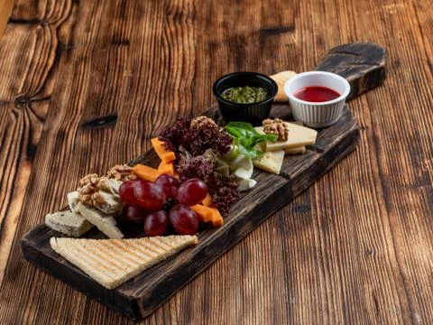 Wine platter with assorted snacks such as grissini, cheese, sliced meat and n Stock Photos