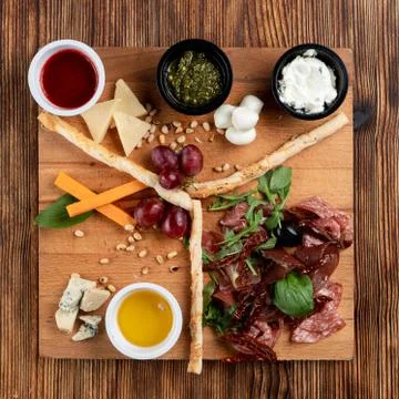 Wine platter with assorted snacks such as grissini, cheese, sliced meat and n Stock Photos