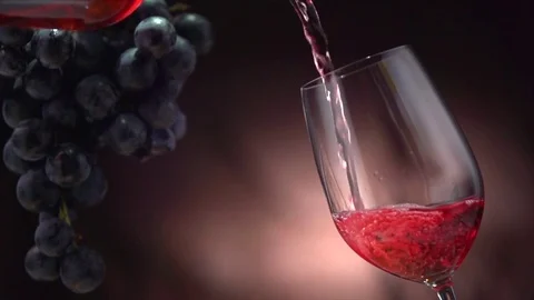 Wine. Red wine pouring in wine glass over dark background Stock Footage 80507526