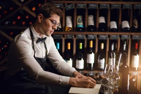 Wine taster writing in notepad information of wine origin and taste. Stock Photos