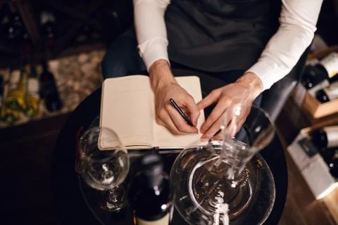 Wine taster writing in notepad information of wine origin and taste. Stock Photos