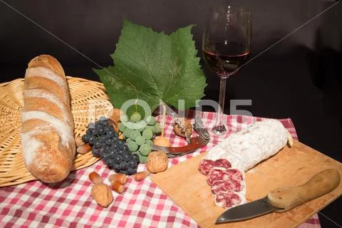 Wineglass with red wine and sausage salame and fruits on black background Stock Photos