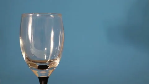 Wineglass on the Table on a Blue Background. Hand Pouring Vodka orTequila. Stock Footage 170381333
