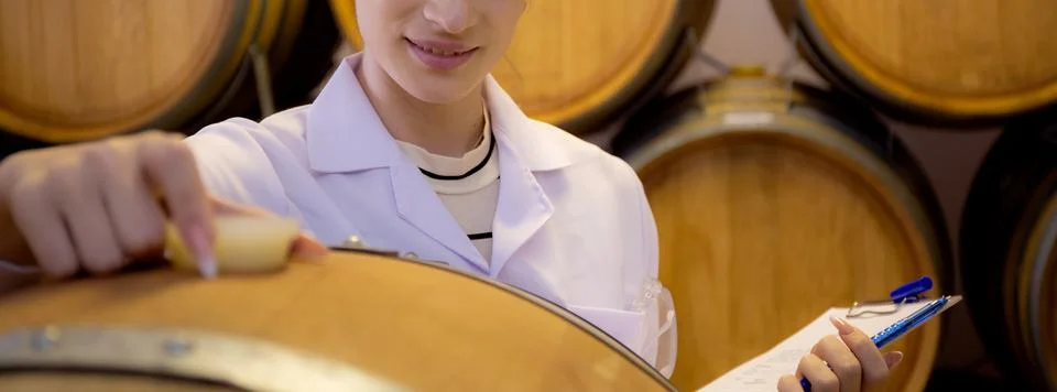 Winemaker woman checking and examining producing wine at winery in factory,.. Stockfoto's