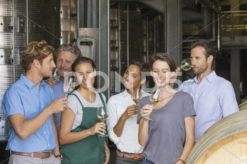 Winery employees tasting white wine in cellar Stock Photos
