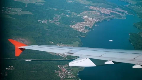 Wing of an aircraft view from the window of the plane flying over the city and Vídeos de archivo 110414934
