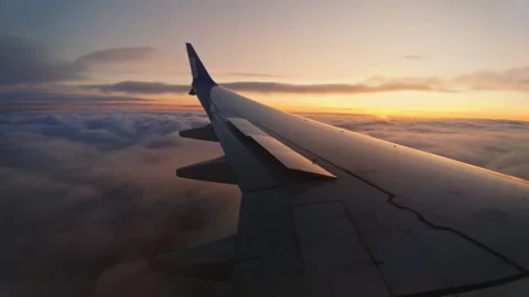The wing of an airplane in the clouds at sunset. view from the window. Stock Footage 242892466