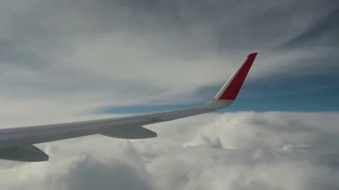 Wing of airplane flies in dense clouds. Blue sky behind Stock Footage 233380716