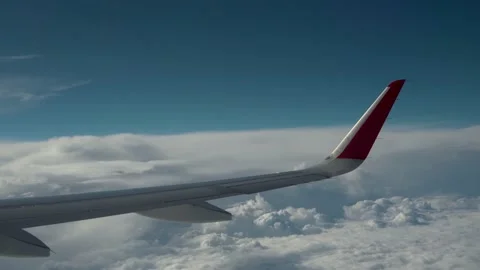 Wing of airplane flies over clouds. Wing returns to its original position after Stock Footage 233810117
