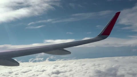 Wing of airplane flies over solid clouds. Rays of sun on wing. Small clouds fly Stock Footage 232361776